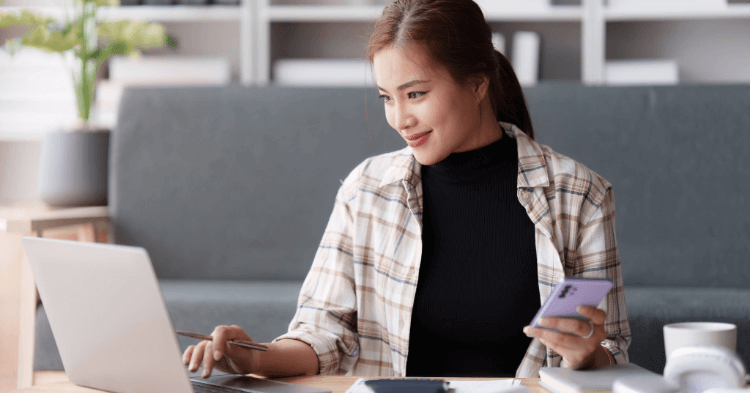 Young women checking her credit on her laptop while holding a phone