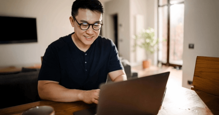 Man with glasses sitting at his laptop in his apartment