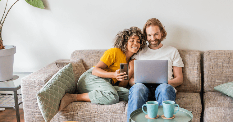 Couple sitting on the couch looking at a laptop