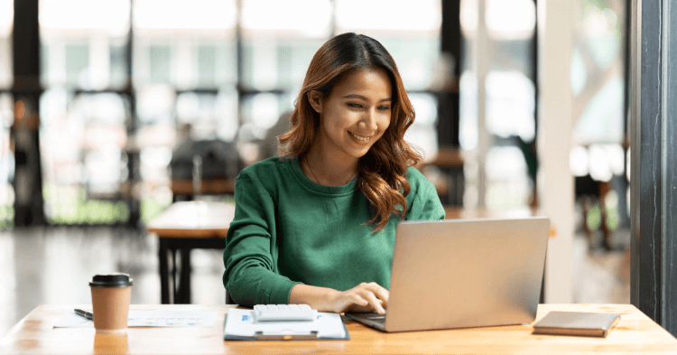 Woman in a coffee shop looking at creditworthiness on a laptop