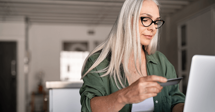Woman holding credit card considering debt consolidation options on her laptop.