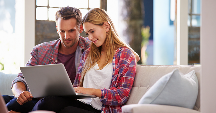 Couple sitting on couch looking at laptop