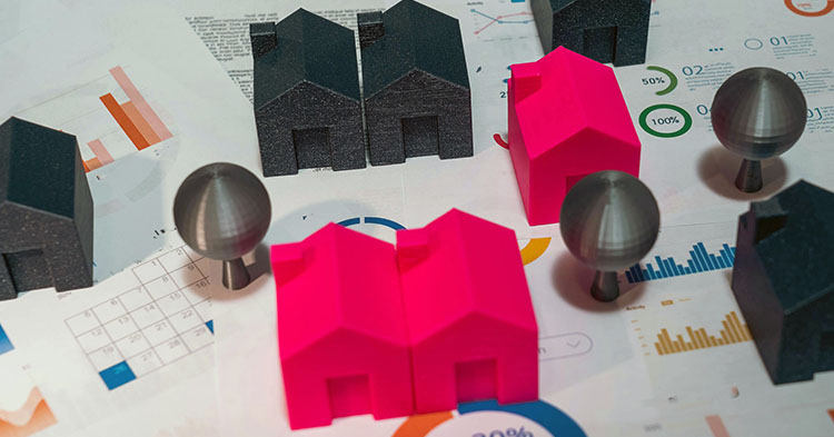 Miniature houses on top of financial planning documents.