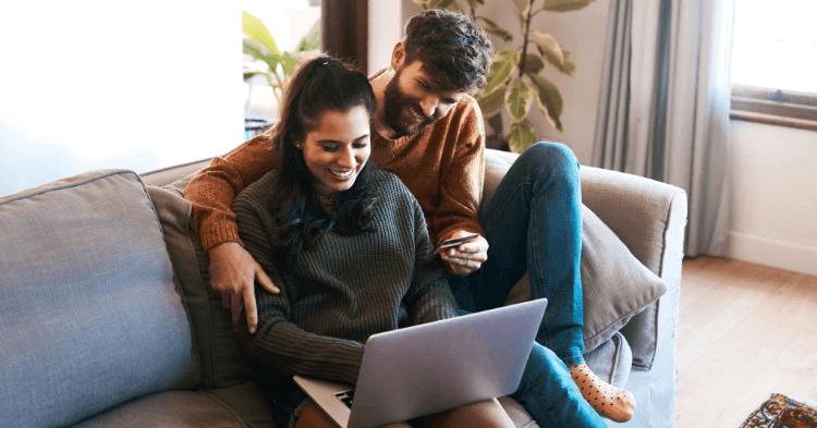 Couple sitting on couch looking at their laptop