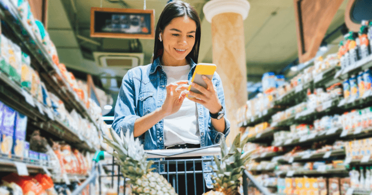 Woman looking at a shopping list on her phone in a grocery store