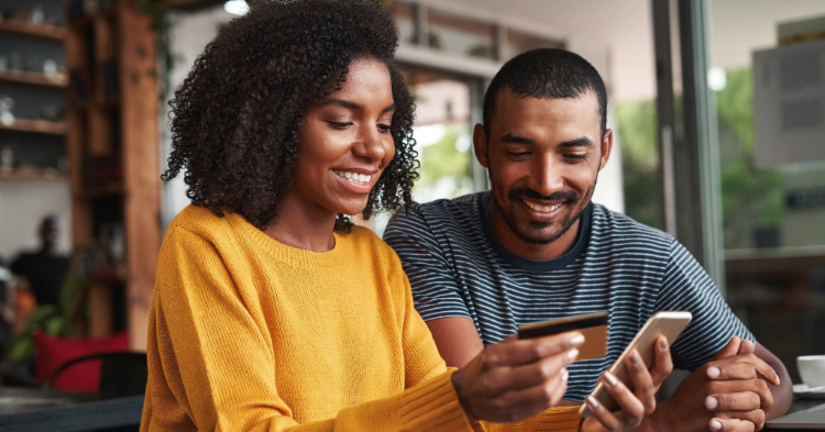 Couple in their home looking at a credit card and phone