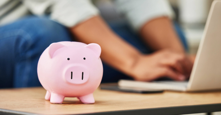 Piggy bank in front of somebody using their laptop