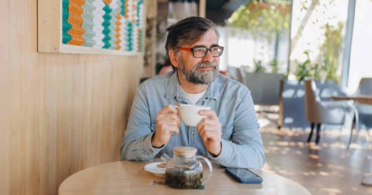 Man in coffee shop wearing a blue shirt.